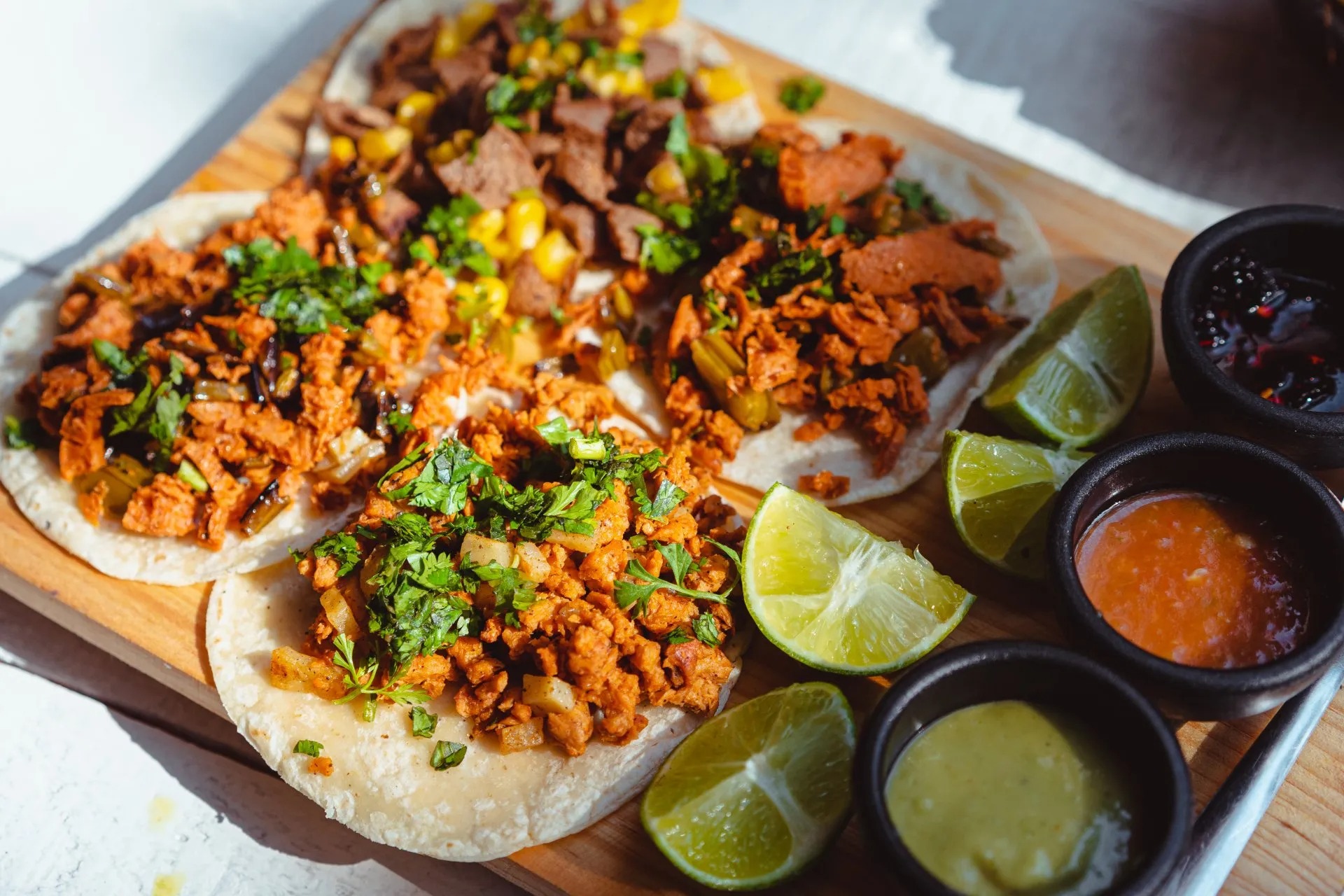 Street tacos with pineapple, corn and lime on a wooden board